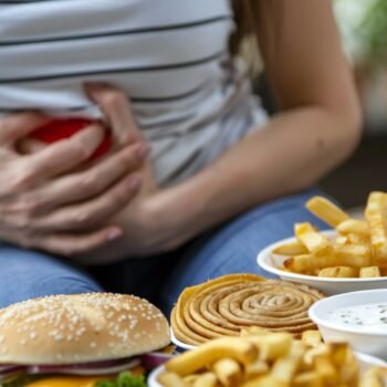 After Consuming Unhealthy Fast Food, Person Suffers from Stomach Heartburn